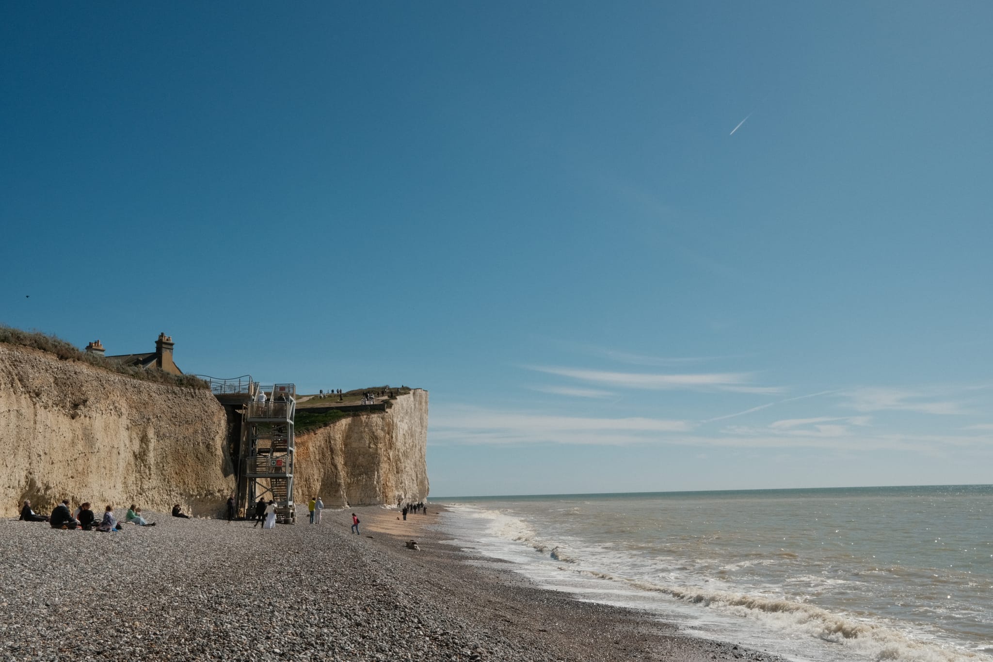 Beneath the Cliffs — Walkers small against the chalk face.