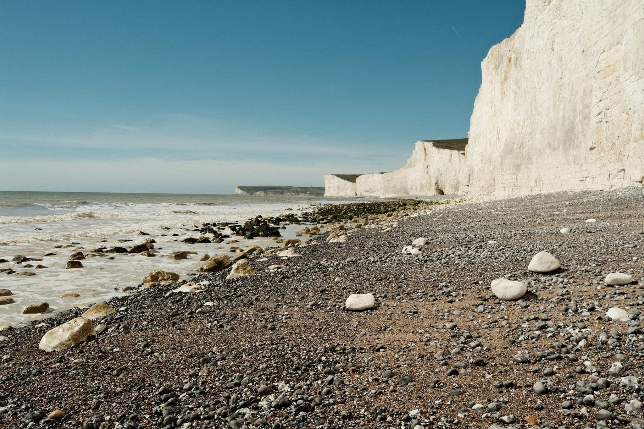 Chalk Coast — White cliffs run east under a clear sky.