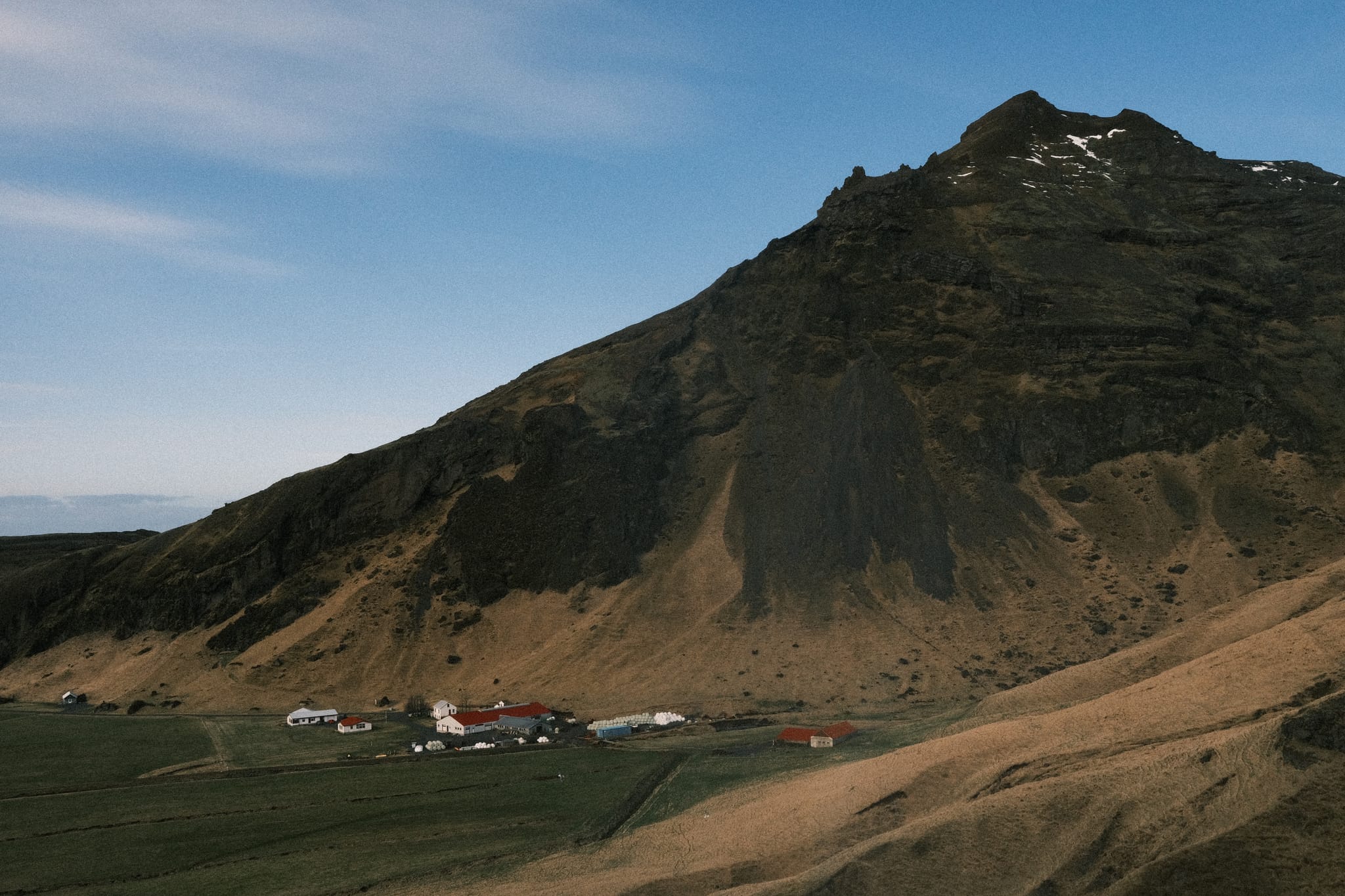 Mountain Farm — A small farm sits below a steep ridge.