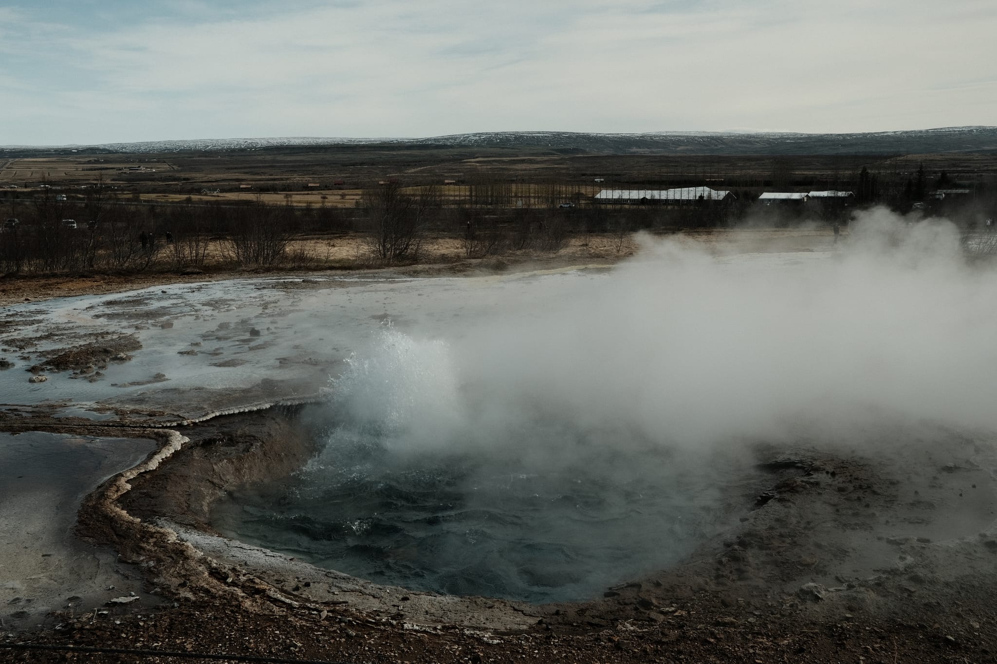 Strokkur — A hot spring boils and steams on the plain.